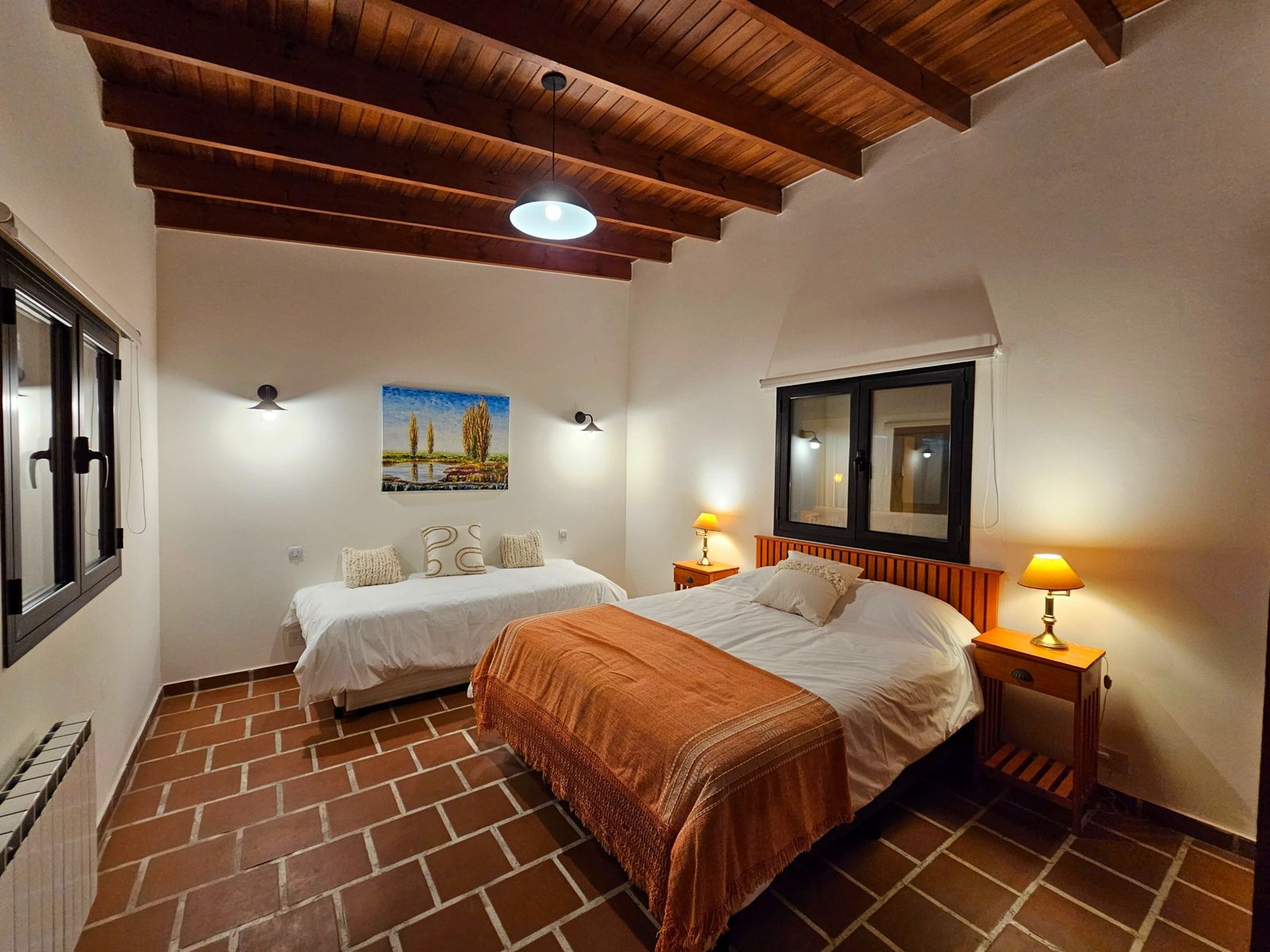 Dormitorio con cama matrimonial, cama individual y techo de vigas