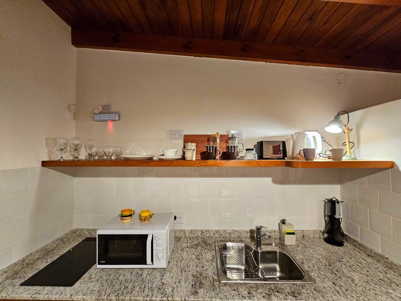 Cocina con anafe, microondas y estantes de madera